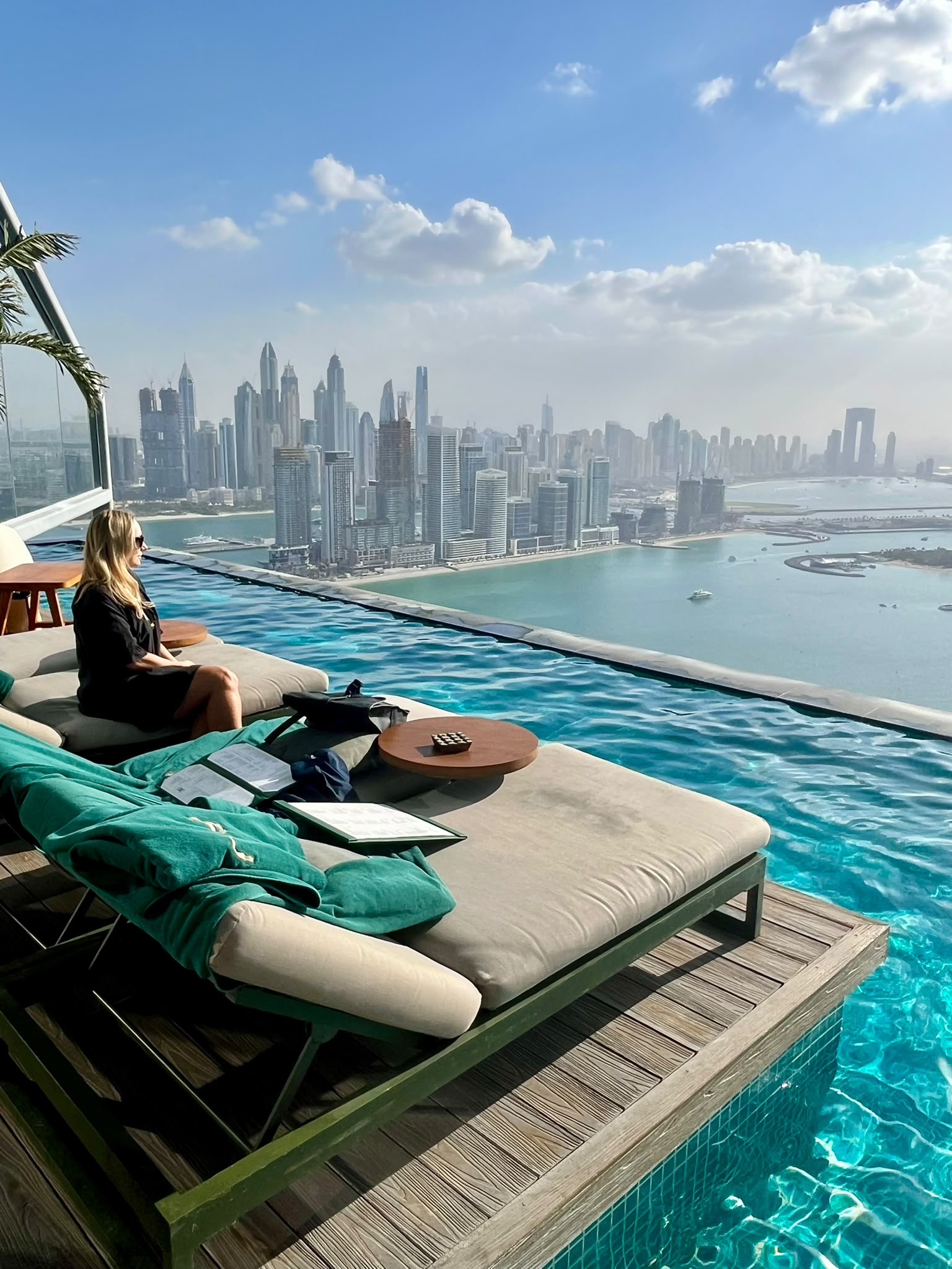 Sandra seated beside an infinity pool overlooking the Dubai skyline